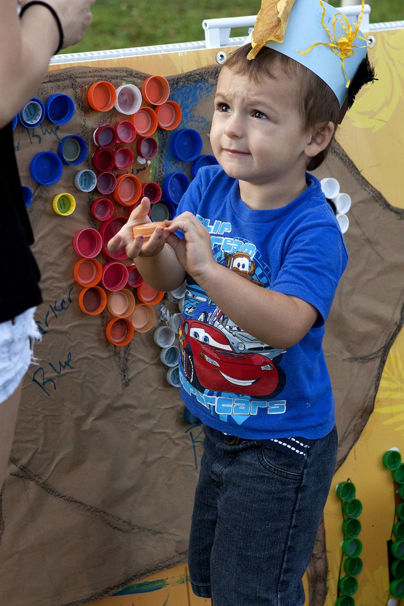 A young child creating recycled bottle-cap art with a grown-up